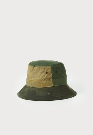 Green and beige bucket hat with a two-tone design, made of durable fabric, featuring stitched accents and a logo label on the side.