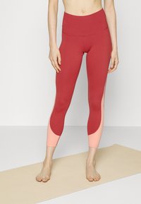 Leggings taille haute en bourgogne rouge avec des panneaux d'accent rose clair ; design élégant, matériau extensible et coupe près du corps.