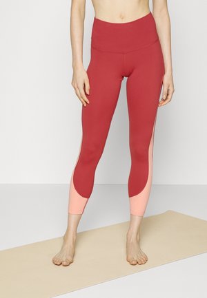 High-waisted leggings in reddish-burgundy with light pink accent panels; sleek design, stretchy material, and close-fitting shape.