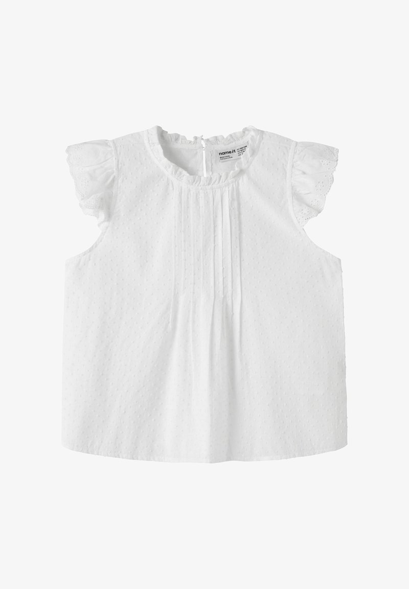 Blouse pour bébé blanche sans manches avec un col volanté et des manches papillon en dentelle ajourée, présentant une texture subtile à pois et des plis sur le devant.