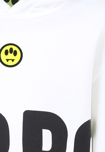 Felpa bianca con grande lettering nero e un grafico circolare giallo che presenta un volto con zanne. Tessuto morbido, design casual.