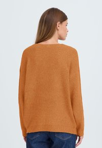 Roodbruin sweater met een structuurpatroon, brede mouwen en een ronde halslijn. De achterkant heeft een iets langere zoom.