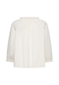 Blouse blanche à manches longues vue de dos, avec encolure et poignets élastiques froncés, coupe ample, sans fermeture ni motif visible.