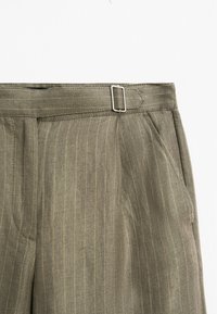 Khaki spodnie z pionowymi paskami, z metalowym zapięciem, bocznymi kieszeniami i teksturowanym materiałem.