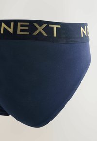 Caleçon pour homme bleu marine avec un logo doré "NEXT" sur la ceinture élastique. Texture lisse, coupe ajustée, sans coutures ni motifs visibles.