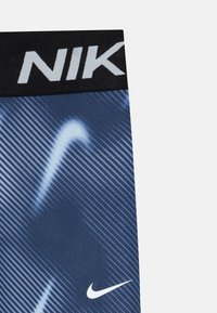 Fekete derékpántos Nike leggings, kék gradiens mintával és fehér kiemelő vonalakkal; a szegély közelében fehér Nike logóval.