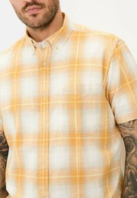 Korte mouwen geruite shirt in oranje en wit, met een button-down kraag en een borstzak. Gemaakt van katoen met een ruitpatroon.