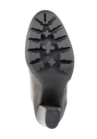 Gumowa podeszwa z głębokim bieżnikiem, z płaskim obcasem. Materiał jest teksturowany i elastyczny, zaprojektowany dla przyczepności i trwałości.