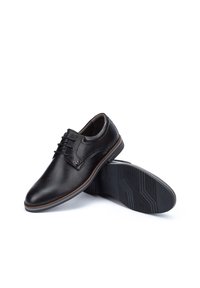 Chaussures de ville en cuir noir avec un bout arrondi, un laçage et une semelle en caoutchouc dotée d'un motif de grip texturé.