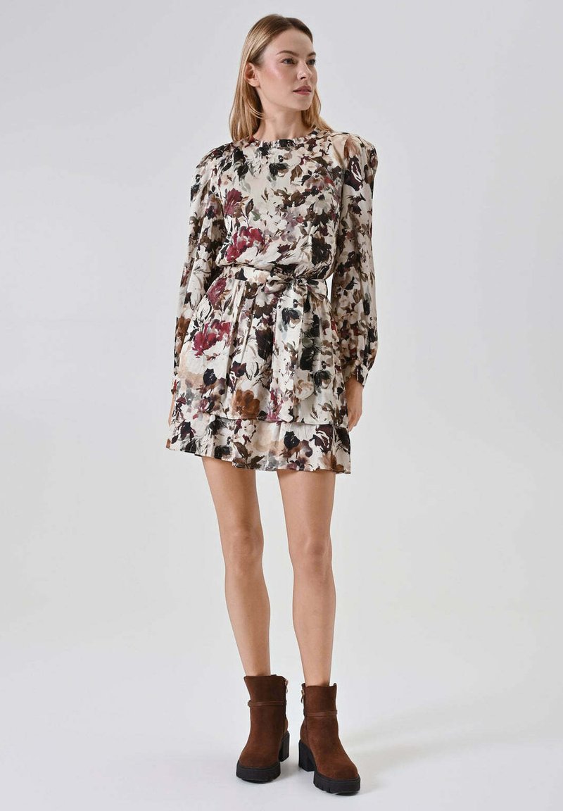 Vestito floreale con maniche lunghe, vita aderente e gonna a strati. Presenta uno sfondo crema chiaro con motivi floreali rosso scuro e verde.