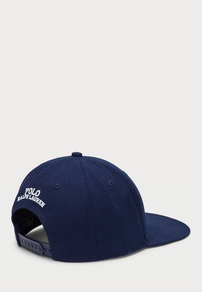 Casquette marine avec une visière courbée, fabriquée en coton. Dotée d'un texte brodé en blanc "POLO RALPH LAUREN" à l'arrière et d'une lanière adjustable.