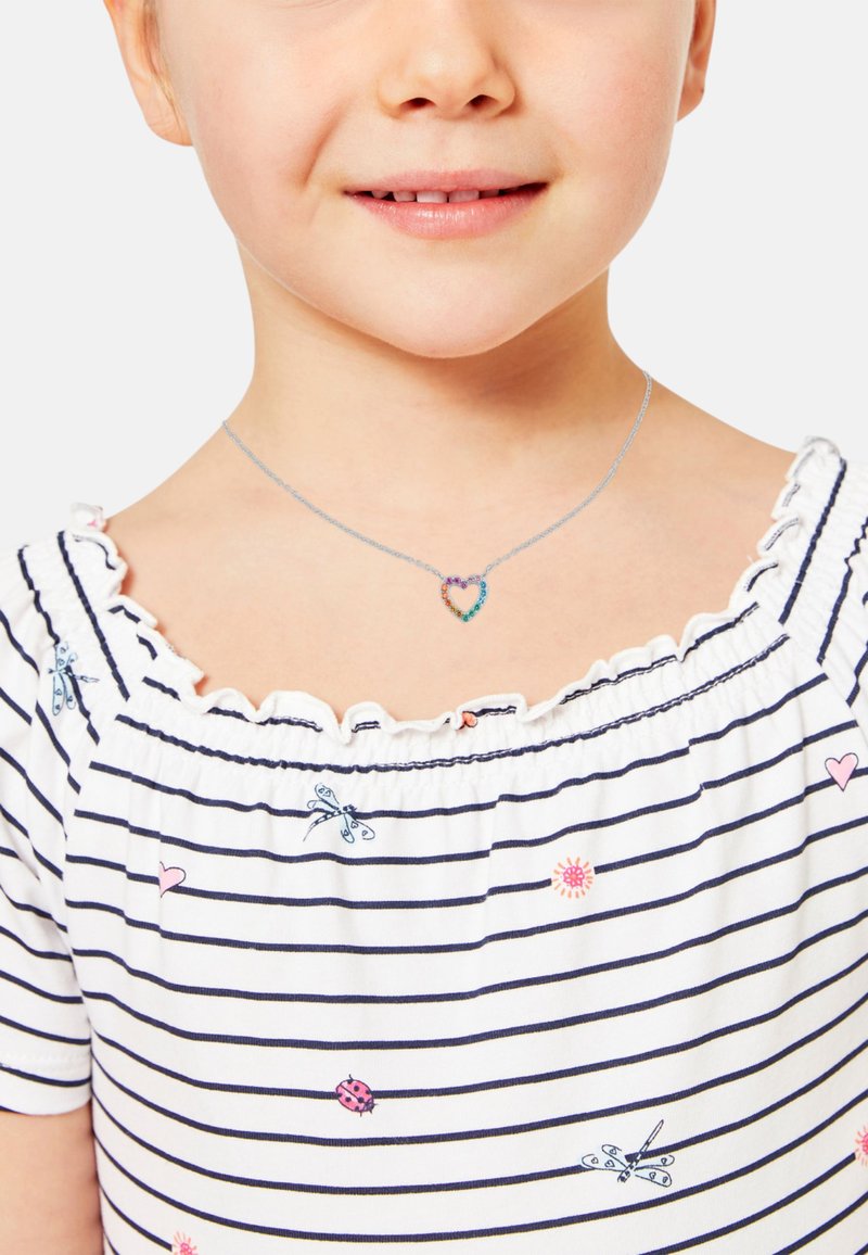 Collana d'argento con un pendente a forma di cuore decorato con pietre multicolori. Bambina che indossa una maglietta a righe bianche e blu navy con scollo a rouches.