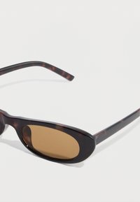 Γυαλιά ηλίου με σχέδιο χελώνας, οβάλ καφετί φακούς, λεπτά μπράτσα και λεία επιφάνεια. Διαθέτουν διακριτικό μοτίβο στο σκελετό.