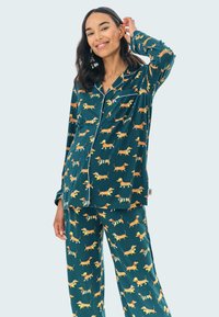Conjunto de pijama con estampado de teckel en tejido azul oscuro, que incluye una camisa de botones y pantalones a juego con ilustraciones de perros juguetones.