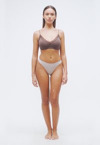 Καφέ μπραλέτο με δαντέλα και ανοιχτό καφέ ψηλόμεσο εσώρουχο· λείο ύφασμα· ταιριαστά χρώματα· χωρίς ορατά μοτίβα· μινιμαλιστικός σχεδιασμός.