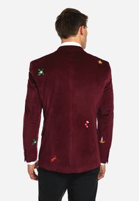 Burgundy velvet blazer with embroidered festive motifs, including mistletoe, a gold star, a candy cane, and a candle, with peaked lapels.