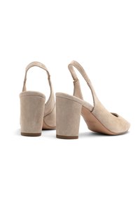 Beige suede slingback heels with a rounded toe and a cutout design. Features a block heel and a buckle closure at the ankle.