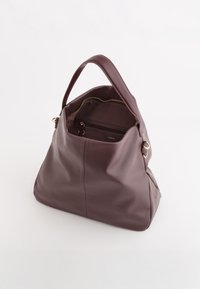 Brązowa skórzana torebka o luźnym fasonie, z górnym uchwytem, złotym zamkiem błyskawicznym i wewnętrzną kieszenią. Gładka tekstura z delikatnymi krzywiznami.