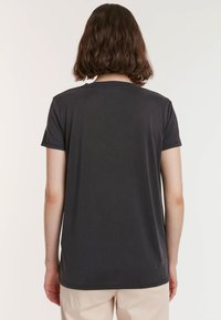 Donkergrijze korte mouwen t-shirt met een ronde hals, een soepele textuur en een eenvoudig ontwerp. Gezien vanaf de achterkant, die de pasvorm van het shirt toont.