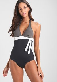 Maillot de bain une pièce avec un col halter, haut gris, ceinture blanche et bas noir. Comprend un détail de lien sur le côté. Matériau lisse et extensible.