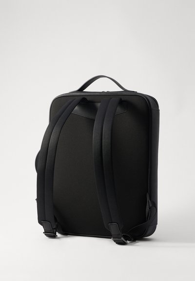Black backpack with padded straps, smooth texture, rectangular shape, and a top handle. Features a zip closure and minimalistic design.