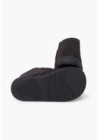 Stivaletto in suede nero con suola in gomma texturizzata, caratterizzato da un design senza lacci e tacco rinforzato. Realizzato in Spagna con materiali resistenti.