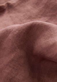 Mekana, naborana tkanina nijanse prigušene mauve boje, koja prikazuje glatku teksturu i ravnomjeran tkanje. Nema vidljivih uzoraka ili ukrasa.