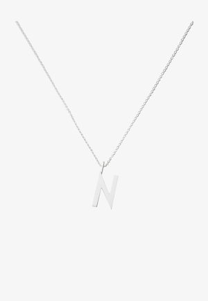 Collier en argent avec un grand pendentif en forme de lettre 'N' majuscule découpée, suspendu à une chaîne délicate. Design simple et moderne.