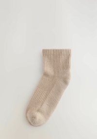 Beige ribbad strumpa med en mjuk textur, med en fållad topp och ett slätt fotområde, designad för komfort och passform.