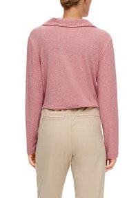 Różowa bluzka z długim rękawem, szerokim kołnierzem, miękką teksturą i luźnym krojem, w połączeniu z beżowymi spodniami z delikatnymi tylnymi kieszeniami.