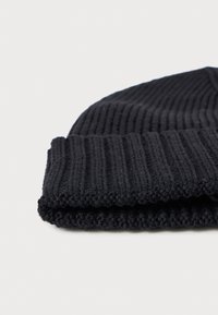 Black knitted beanie with a textured ribbed pattern, featuring a turned-up cuff and a soft, warm fabric.