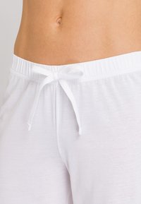 Witte stretchbroek met een elastische tailleband en een trekkoord. De stof ziet er zacht uit met een gladde textuur.