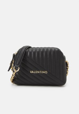 Černá prošívaná kožená crossbody taška se zlatým řetízkem, s diagonálním švem a zlatým logem na přední straně. Kompaktní a strukturovaný design.