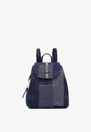 Blue denim patchwork backpack with flap, black leather straps, zipper pocket, and "DERIMOD" logo on front.