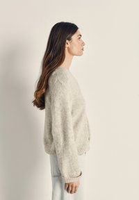 Heledad hallhall, pehmeast riidest, ümmarguse kaelusega ja soonikkrae varrukatega; kantud koos siniste teksadega. Näitab pehmet, tekstuurset kangast, mis on lõtva istuvusega.