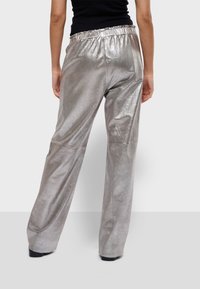 Zilveren metallic wijde broek met een elastische tailleband, kenmerkend door een gladde textuur en een ontspannen pasvorm. Minimalistisch ontwerp en effen kleur.