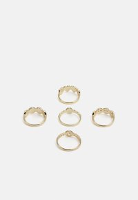 Conjunto de cinco anéis de ouro com diferentes designs, incluindo bordas onduladas e superfícies lisas, dispostos em uma pilha.