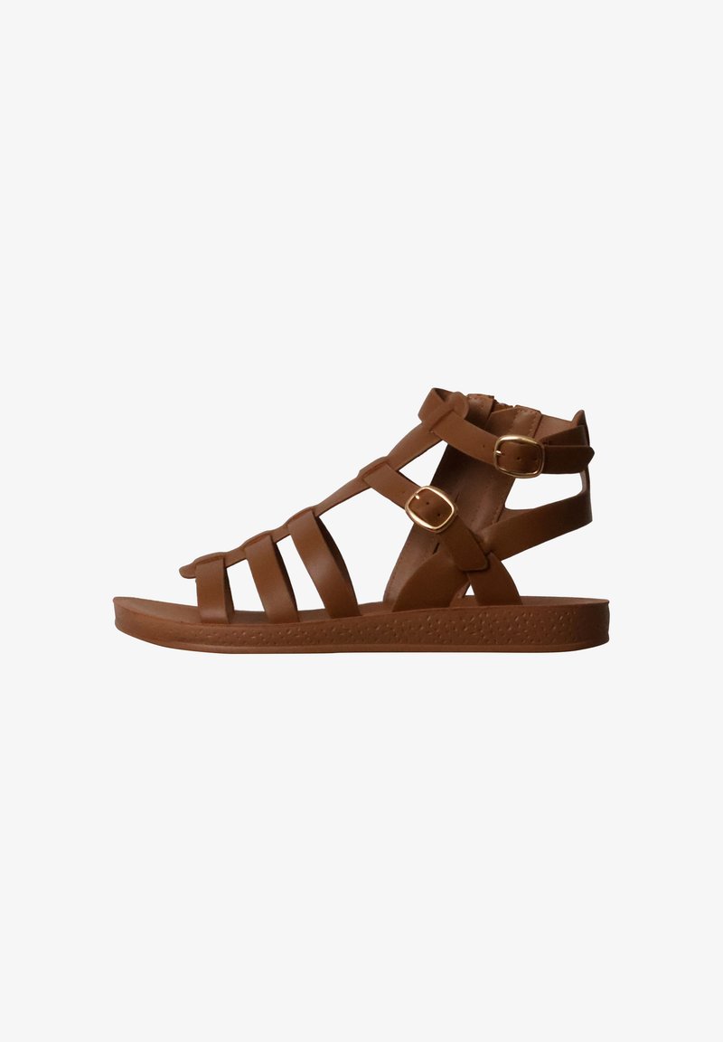 Sandale plate en cuir marron avec plusieurs brides et deux boucles dorées, vue de profil sur fond blanc.