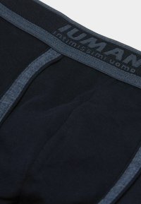 Mörkblå herrunderkläder med en texturerad midjeband märkt "HUMAN". Har kontrasterande grå sömmar och en slät tygfinish.