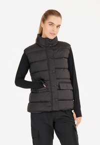 Svart vadderad väst med hög krage, framsnappar och en klaffficka. Slät textur, lätt material, utformat för lager på lager.