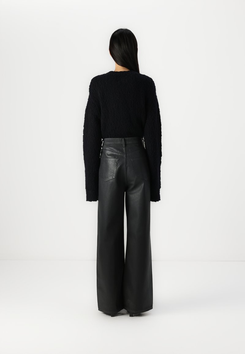 Maglione nero a maglia con maniche lunghe e un design testurizzato, abbinato a pantaloni in pelle nera a vita alta con gamba larga e tasche posteriori.