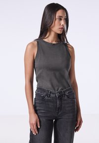 Donkergrijze mouwloze top met een ronde halslijn, voorzien van subtiele kraalversieringen, gecombineerd met hoge zwarte jeans.
