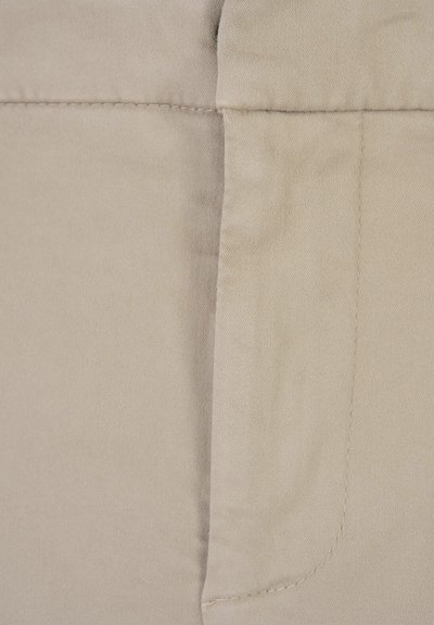Tessuto beige con una superficie liscia, caratterizzato da cuciture dritte lungo una cucitura, creando un design pulito e semplice.