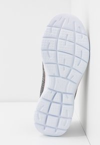 Athletic shoe sole featuring a textured white rubber pattern, with a gray fabric upper and a subtle pink accent along the side.