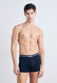 Navy boxer shorts made from a soft material, featuring a fitted design and an elastic waistband with white "BOSS" branding.