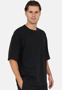 Zwart T-shirt van katoen, met korte mouwen, een ronde hals en een losse pasvorm. Glad oppervlak zonder zichtbare patronen of accenten.