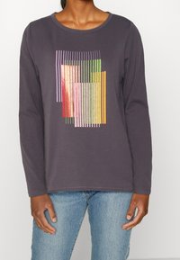 Langärmliges, dunkelgraues Baumwollhemd mit einem bunten geometrischen Druck, der vertikale Linien in Rosa, Grün, Orange und roten Akzenten zeigt.