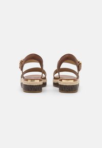 Bruna lädersandaler med en flätad espadrille-sula, justerbart ankelsnöre och detaljer i guldton. Texturerad logotyp på fotbädden.