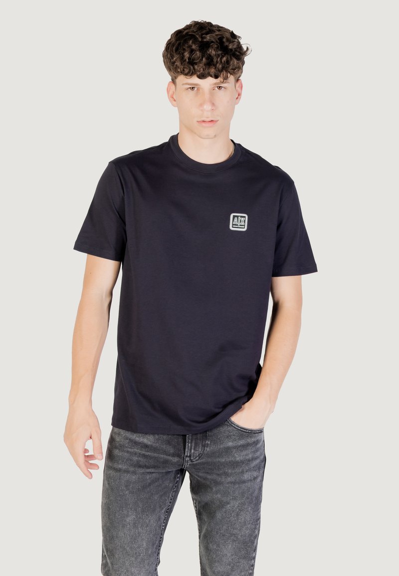 T-shirt in cotone blu navy con maniche corte e scollatura rotonda, caratterizzato da una piccola patch con logo sul petto sinistro e una vestibilità rilassata.