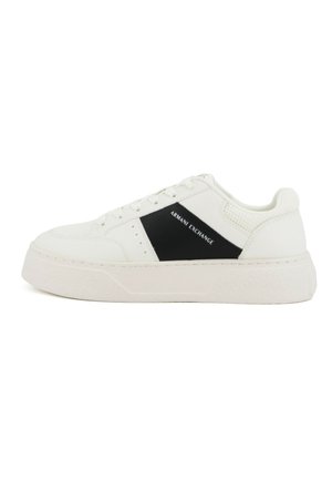 Zapatilla blanca de corte bajo con panel lateral negro y marca "Armani Exchange", cierre de cordones y suela gruesa texturizada.
